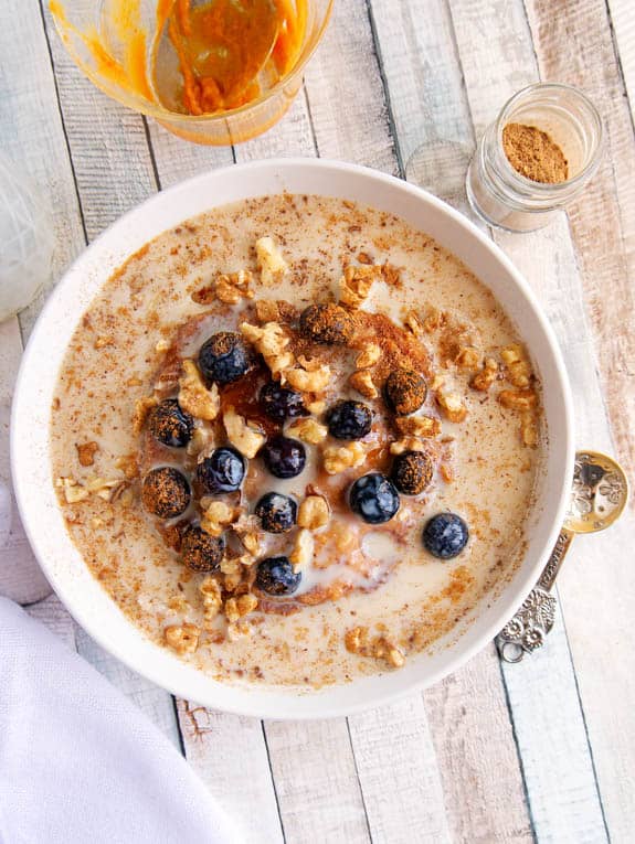 Top shot of Cinnamon and Spice Oatmeal with berries and pumpkin in a white bowl