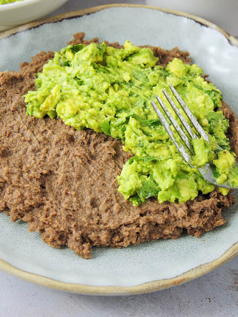mashed avocado mixture spread on top of refried black beans