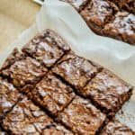 Chocolate fudge brownies with walnuts cut into squares, presented on parchment paper