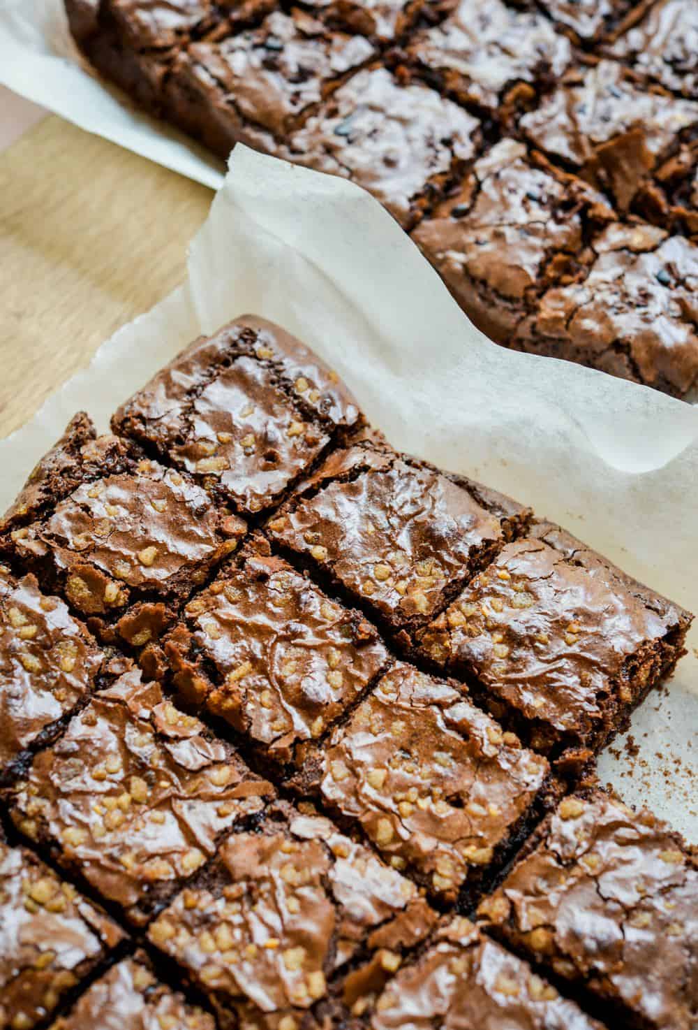 Chocolate fudge brownies with walnuts cut into squares, presented on parchment paper