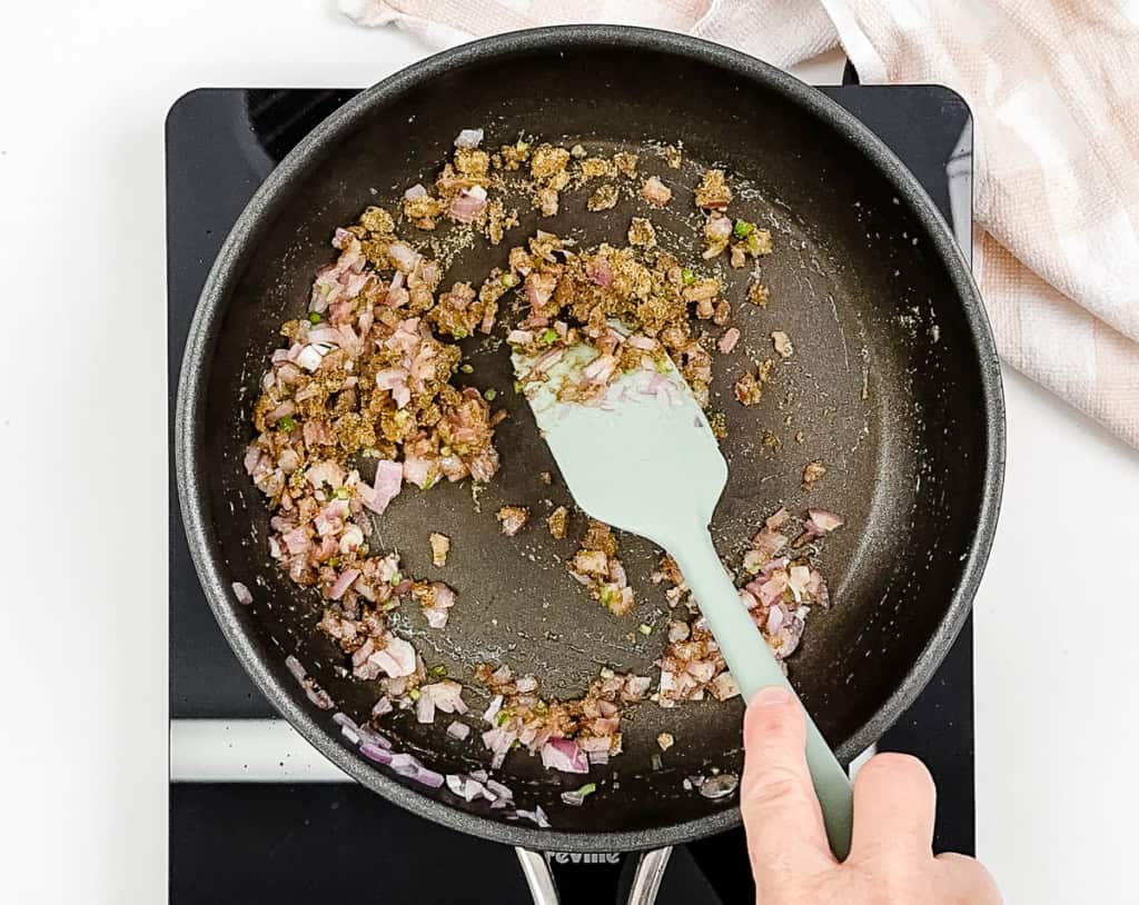 Onions and spices sauteeing in a pan on the stove.