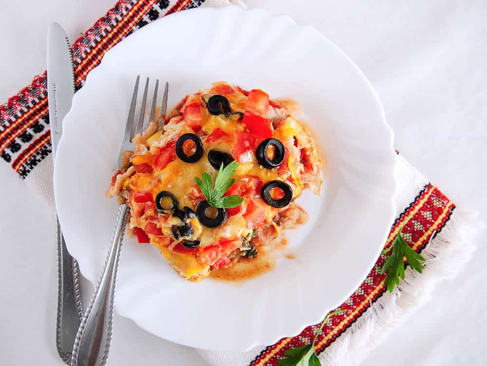 vegetarian taco lasagna recipe, a piece cut and pictured on a white plate, top view