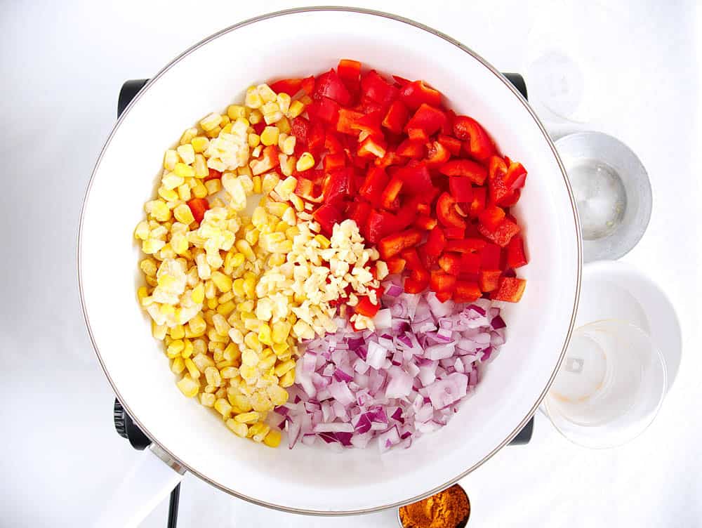 Red onion, red pepper, garlic and corn sauteed in a pan