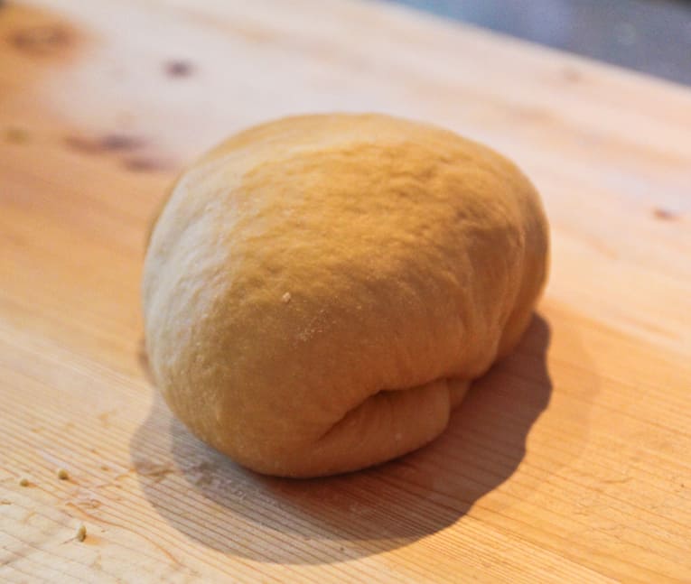 A kneaded ball of dough on a wooden board