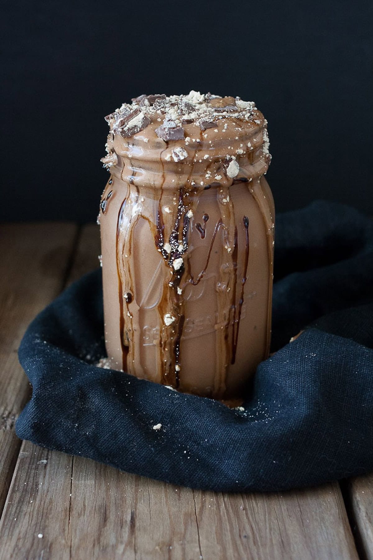 vegan peanut butter cup milkshake in a mason jar with chocolate overflowing from the top