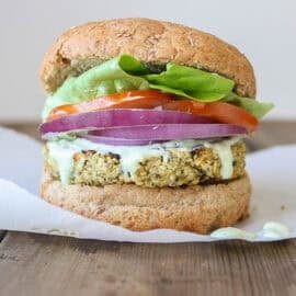 A hemp burger topped with onion, tomato and lettuce in a burger bun.