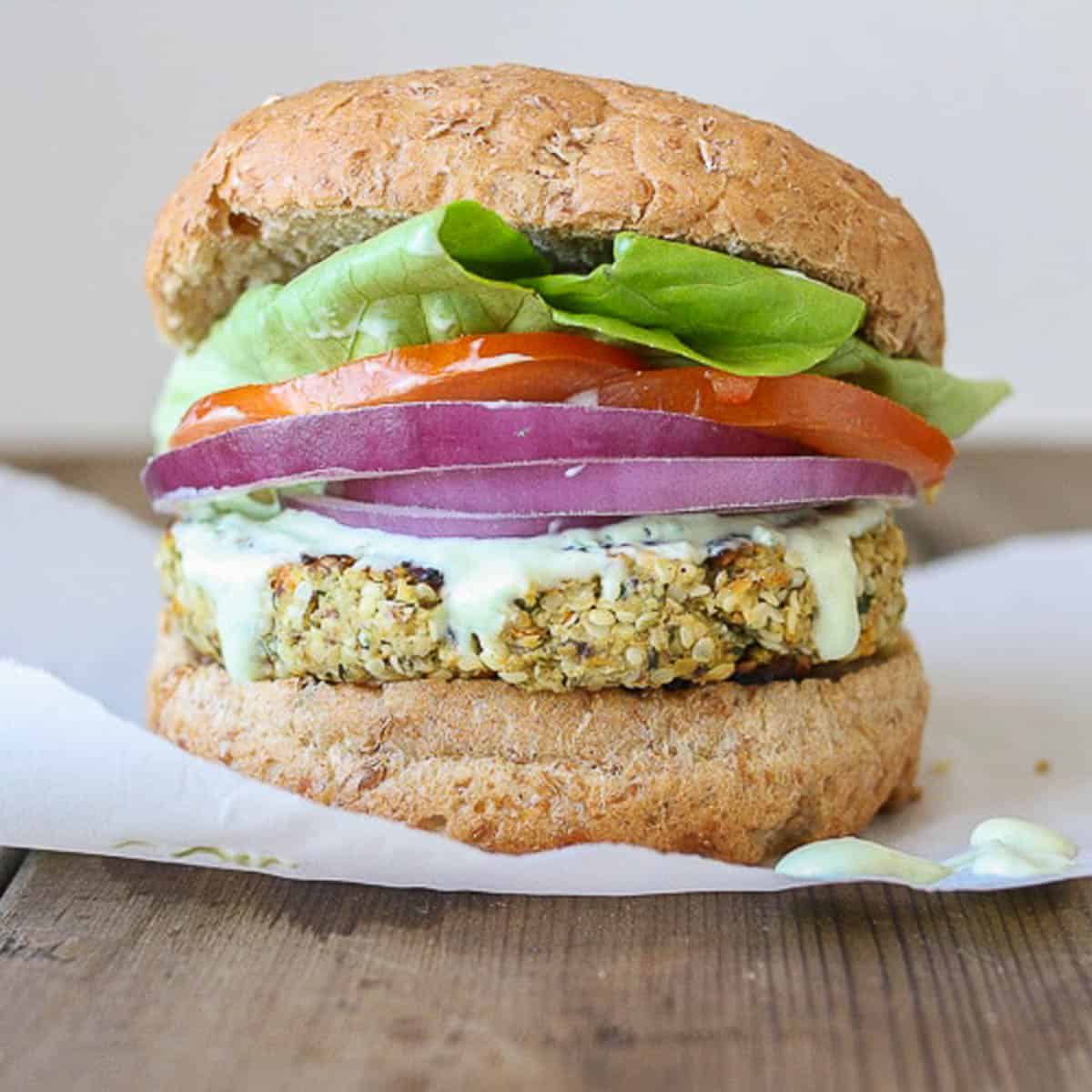 A hemp burger topped with onion, tomato and lettuce in a burger bun.