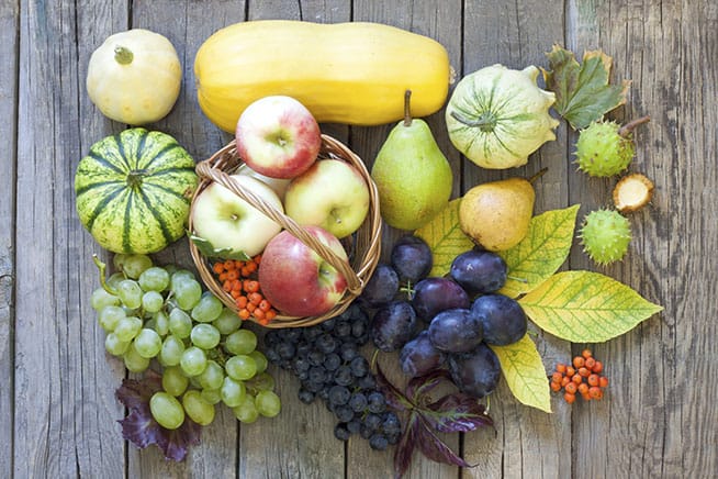 fruit on wood table, apples in basket, grapes, and squash