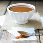 Maple miso balsamic sauce served in a white bowl with a spoon of sauce on the side.