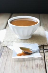 Maple miso balsamic sauce served in a white bowl with a spoon of sauce on the side.