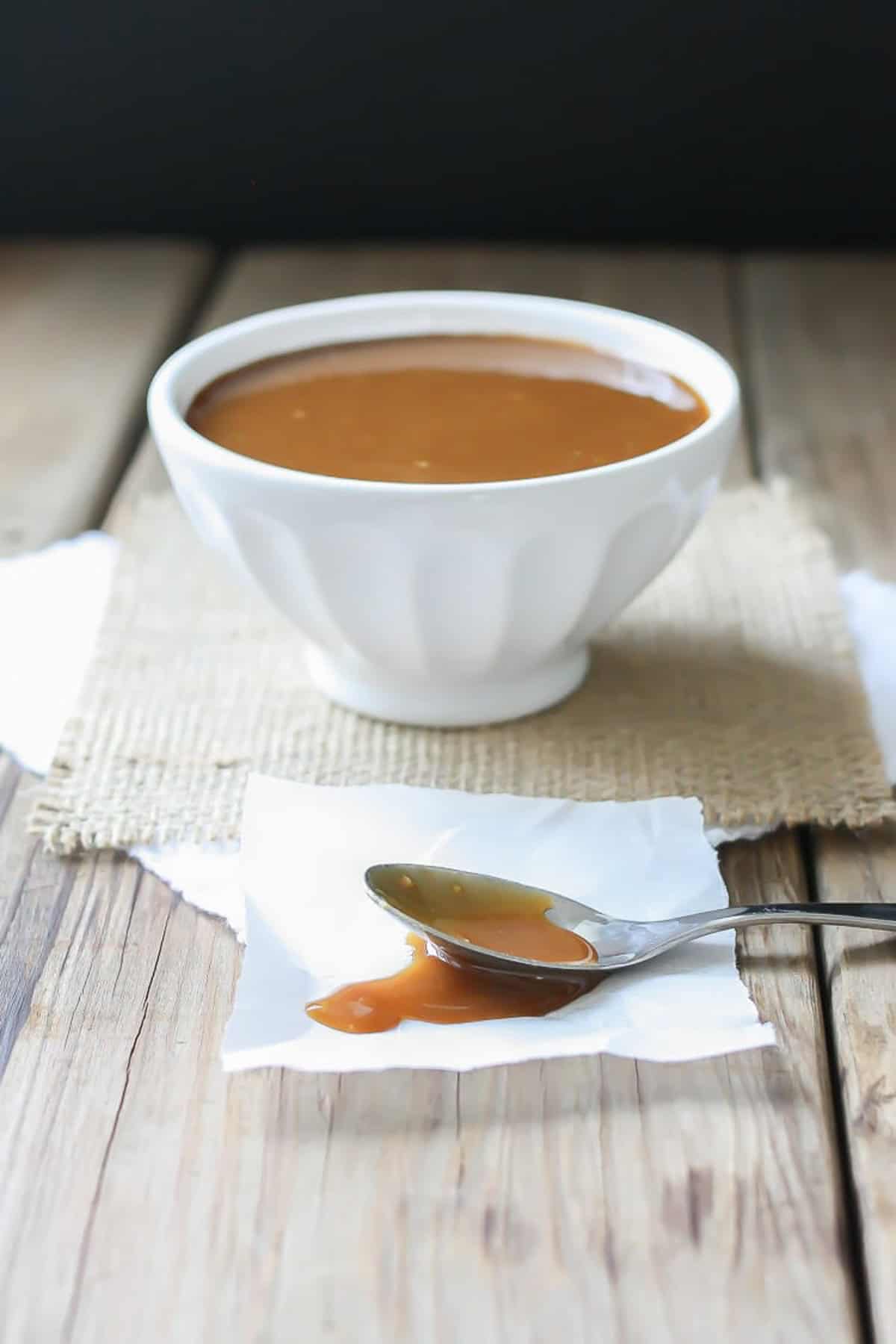 Maple miso balsamic sauce served in a white bowl with a spoon of sauce on the side.