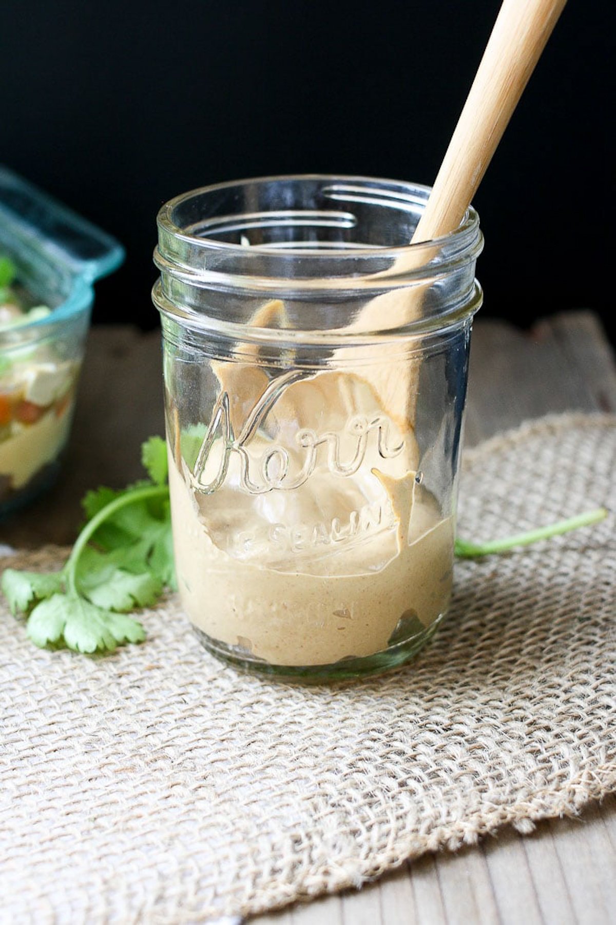 Creamy vegan taco sauce in a glass jar with wooden spoon inside.