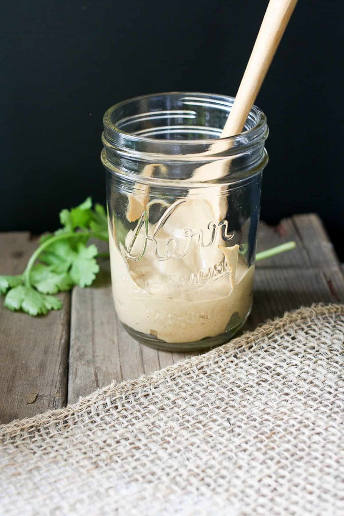 creamy vegan taco sauce in a glass jar with wooden spoon inside