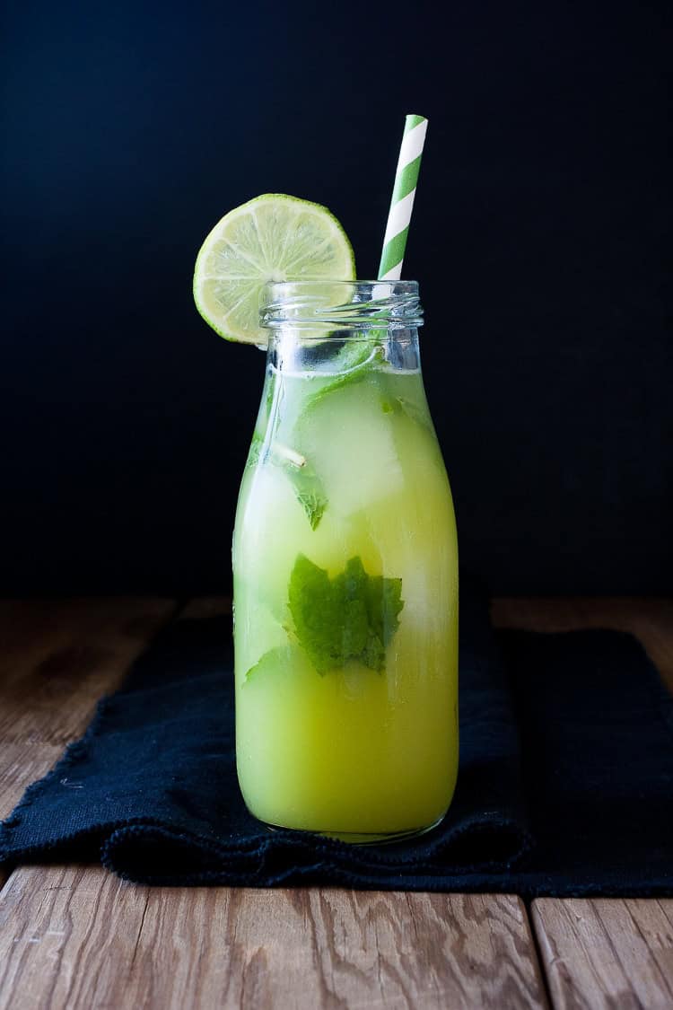 A bottle of Fresh anti-inflammatory juice with a wedge of lime and straw on a wooden surface A bottle of Fresh anti-inflammatory juice with a wedge of lime and straw on a wooden surface