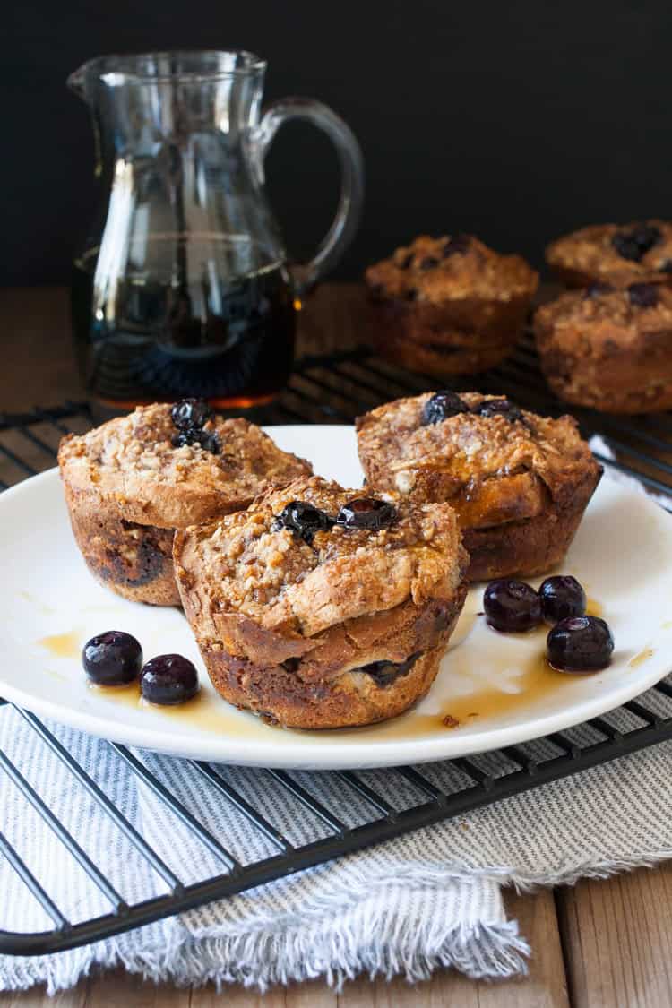 Mixing up breakfast in the most delicious way with blueberry flavored french toast made into vegan breakfast muffins! Easy to put together and prep ahead. #veganbreakfastrecipes #veganmuffins #sponsored #LoveMySilk Three french toast breakfast muffins on a white plate with blueberries