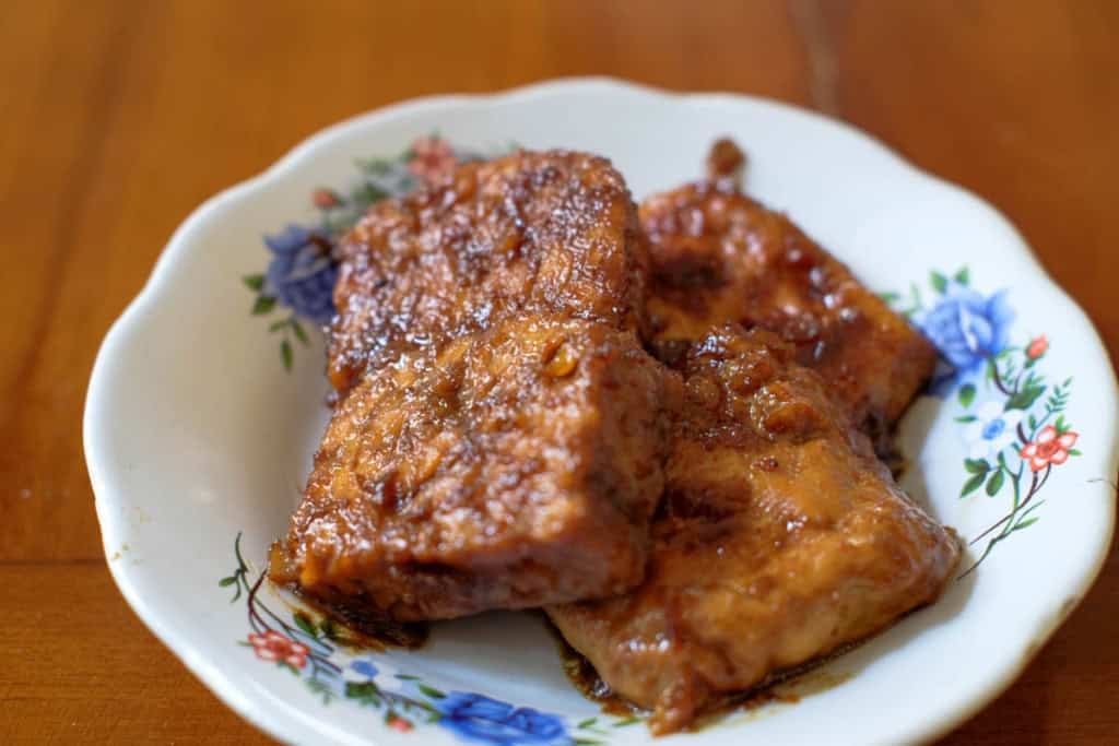 Baked barbecue tempeh slices on a white plate.
