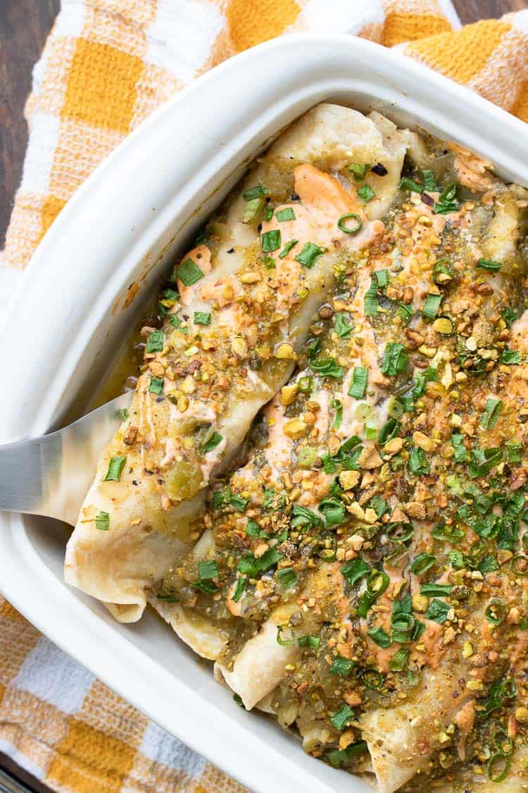 Top view of enchiladas topped with green and pink sauces and green onions