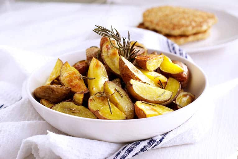 vegan roasted potatoes in a white bowl with rosemary