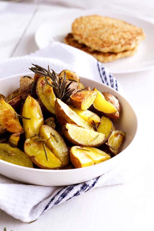 vegan roasted potatoes in a white bowl with rosemary
