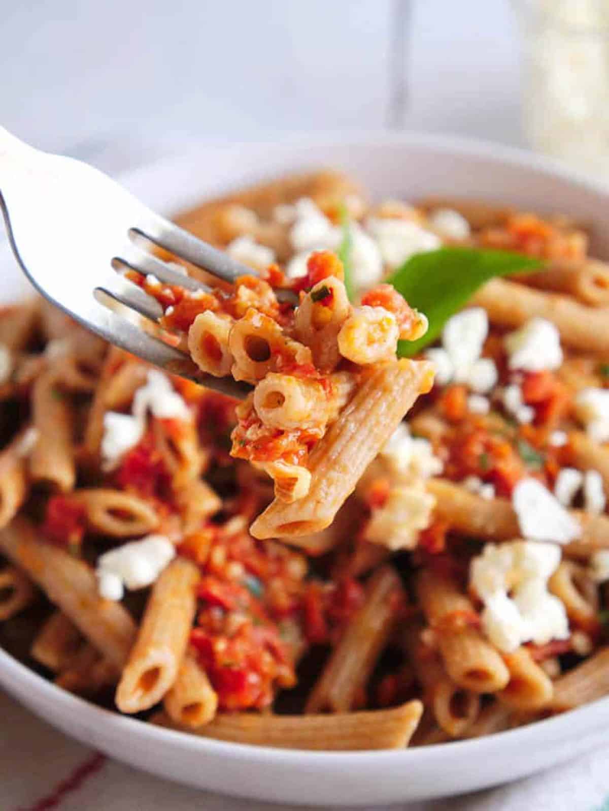 Fork-ful of pasta with sun dried tomatoes and feta cheese.