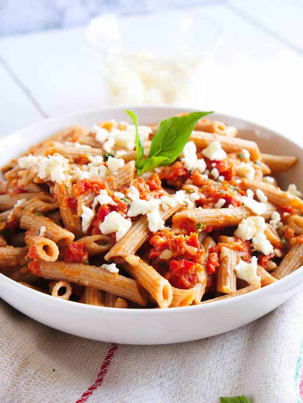 Feta sun dried tomato pasta served in a white bowl.