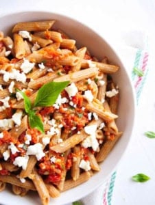 Sun dried tomato feta pasta served in a white bowl.