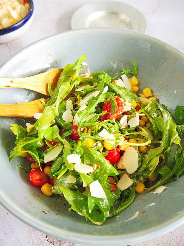 spinach and arugula salad with Tomatoes and Goat Cheese served in a light blue salad bowl