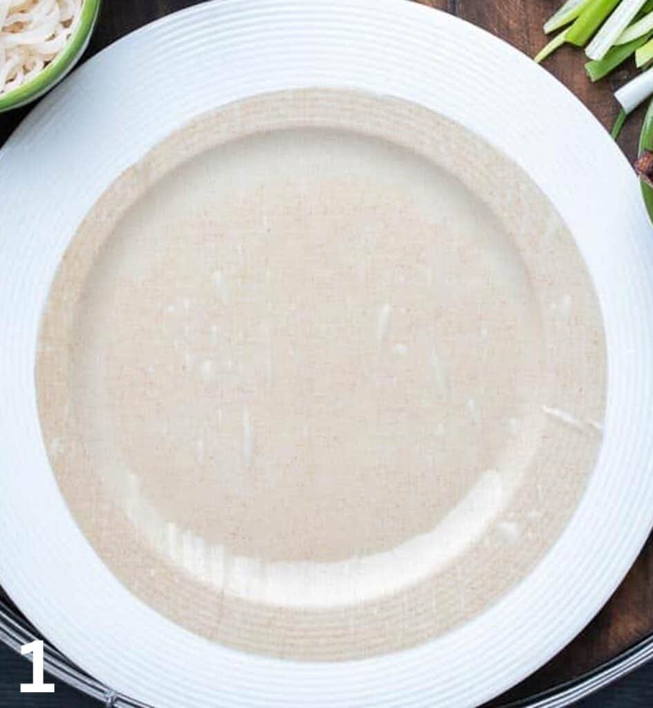 Soaked rice paper on a white plate.