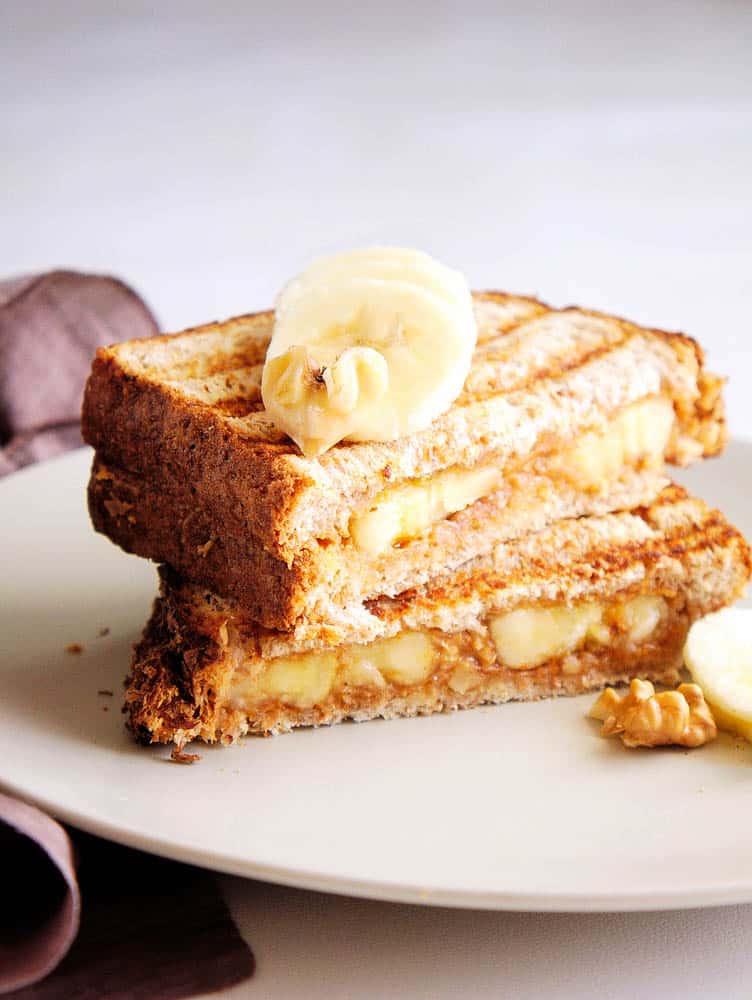 a banana peanut butter sandwich served on a white plate