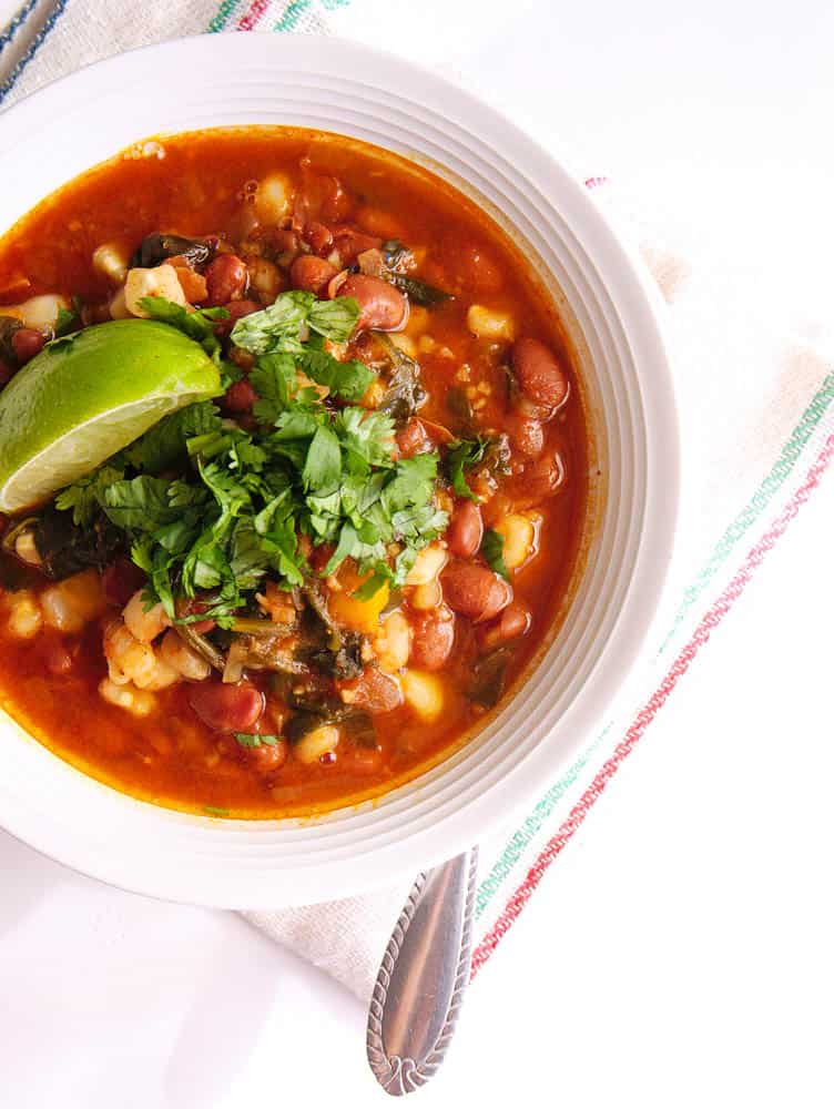 Instant Pot Pinto Beans Vegan Posole in a white bowl served with a spoon