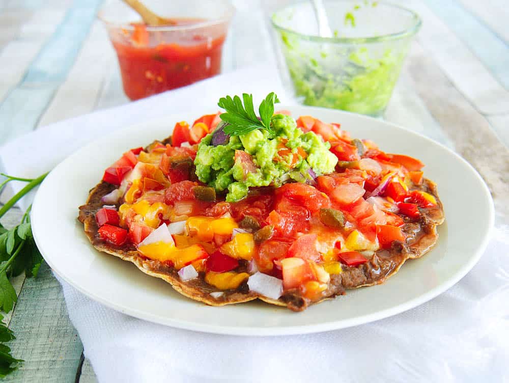 Healthy Copycat Taco Bell Mexican Pizza topped with salsa and guacamole, served on a white plate