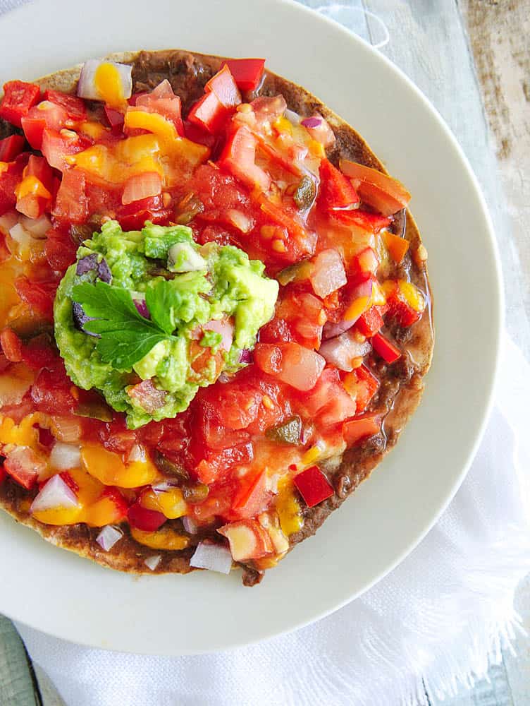 Healthy Copycat Taco Bell Mexican Pizza topped with salsa and guacamole, served on a white plate