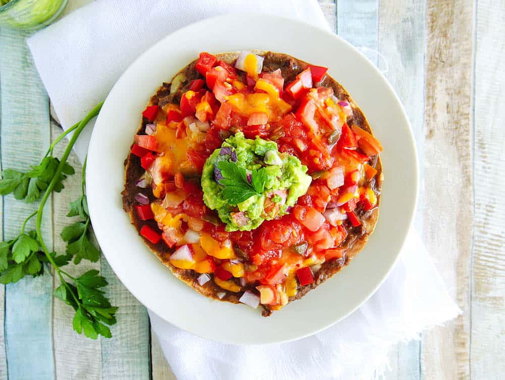 Healthy Copycat Taco Bell Mexican Pizza topped with salsa and guacamole, served on a white plate