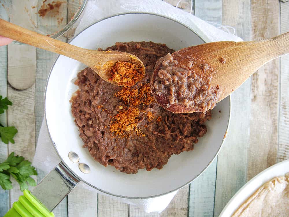 refried black beans mixed with taco seasoning in a white pot