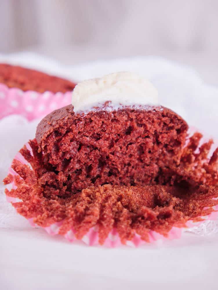 red velvet cupcakes with natural food coloring, with a pink cupcake wrapper against a white background - cut in half