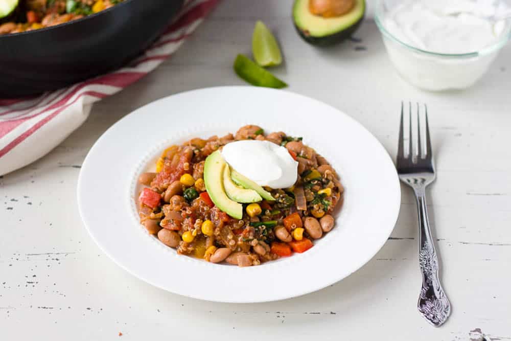 Mexican Taco casserole served in a white bowl with avocado and sour cream