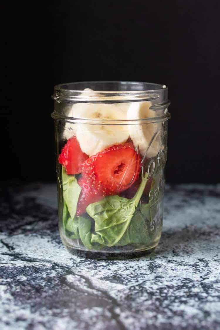 Start your day with this healthy strawberry spinach smoothie with chia seeds for added thickness. The added low fat vegan protein helps keep you full and energized all morning long! #healthysmoothies #veganbreakfast #ad Glass jar layered with spinach, strawberries and banana slices