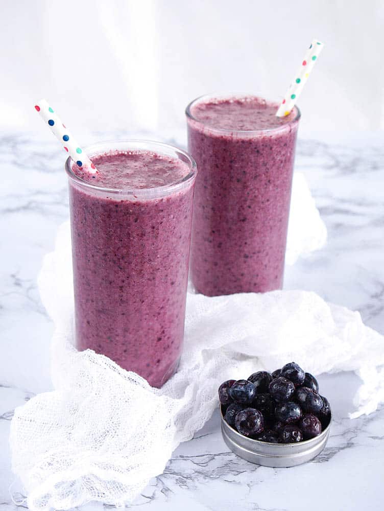 Glasses with blueberry banana smoothie with straws