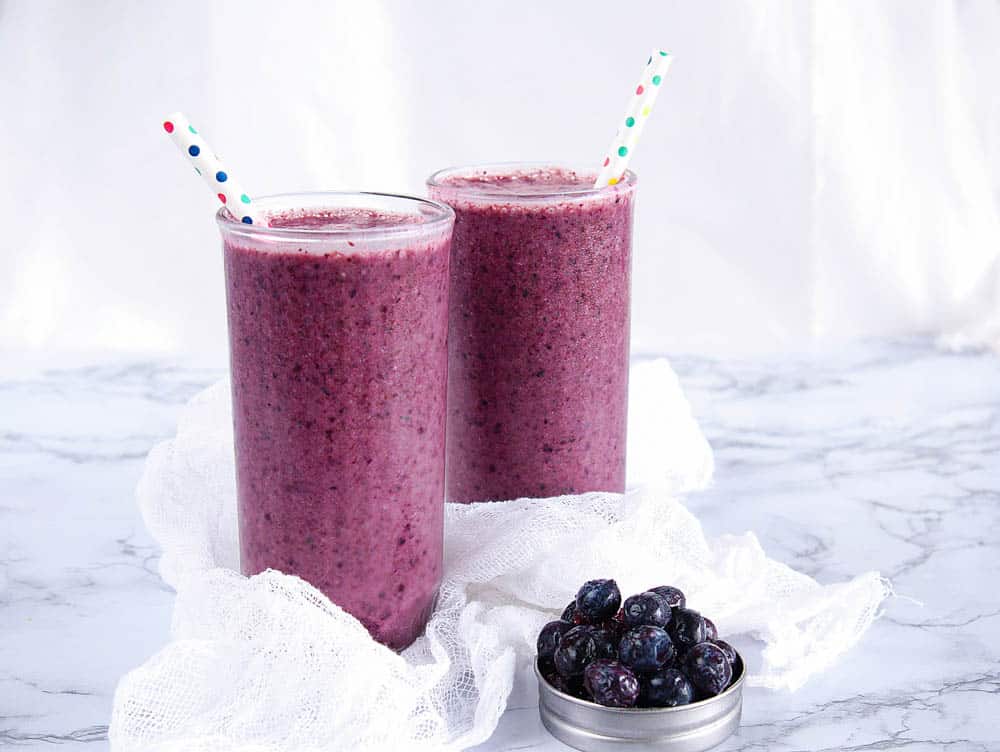 Blueberry banana smoothie in two glasses on a marble work surface