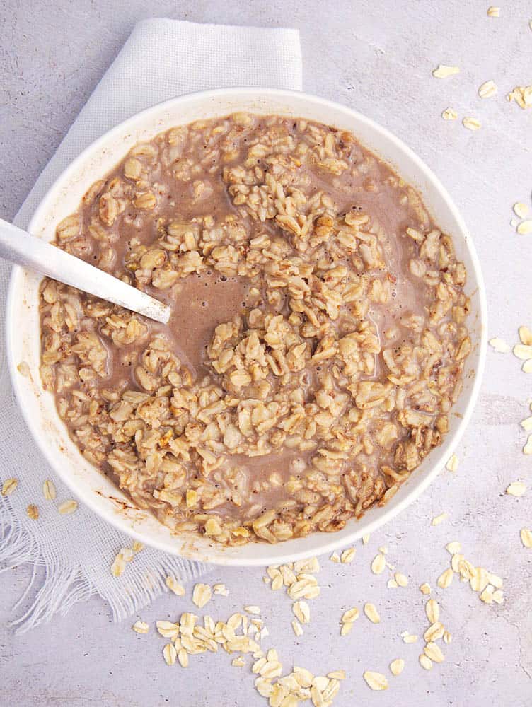 Dark chocolate oatmeal served in a white bowl, with a spoon