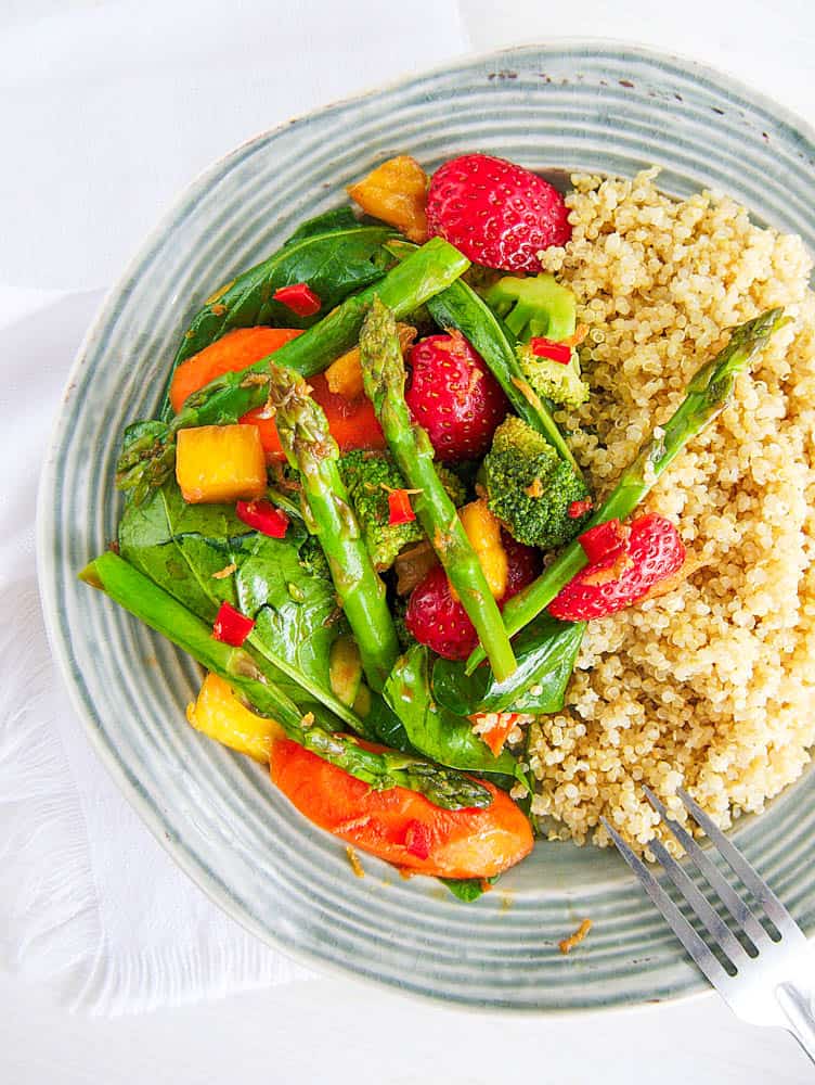 Healthy vegetable stir fry sauce with veggies served with quinoa on a glass plate