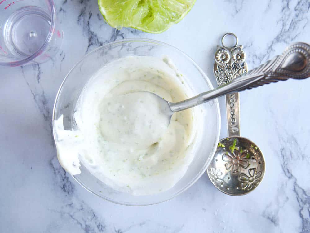 greek yogurt / sour cream sauce mixed with lime zest in a glass bowl, top view