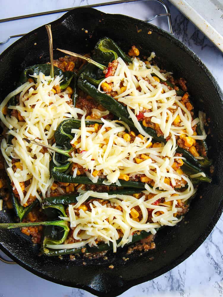 cheese added to vegetarian stuffed poblano peppers, right before going into the oven, placed in a cast iron skillet