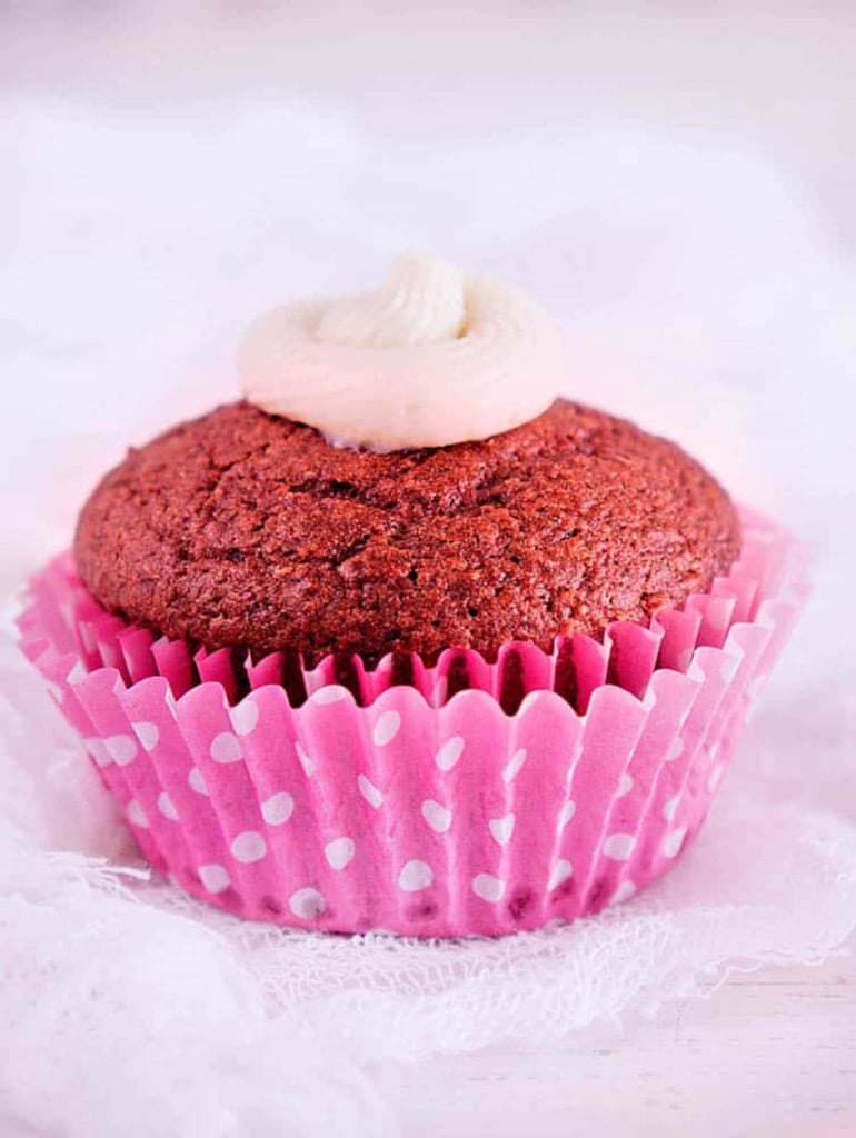Healthy red velvet cupcakes on a white countertop with a pink cupcake wrapper.
