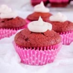 Healthy red velvet cupcakes on a white countertop with a pink cupcake wrapper.