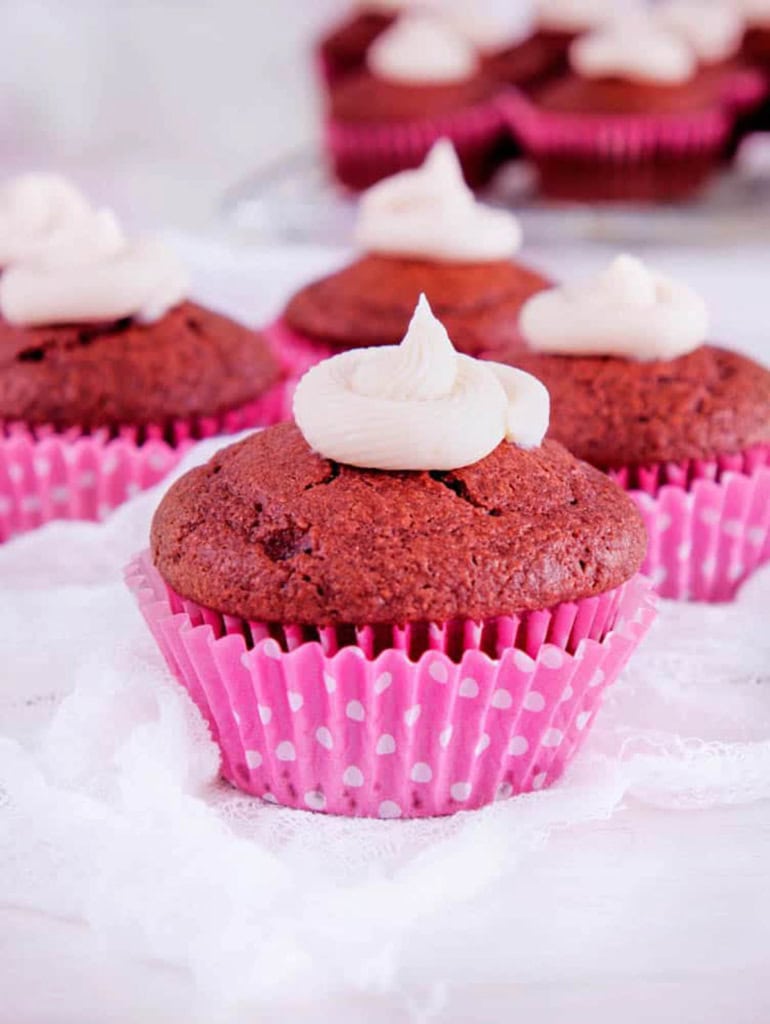 Healthy red velvet cupcakes on a white countertop with a pink cupcake wrapper.