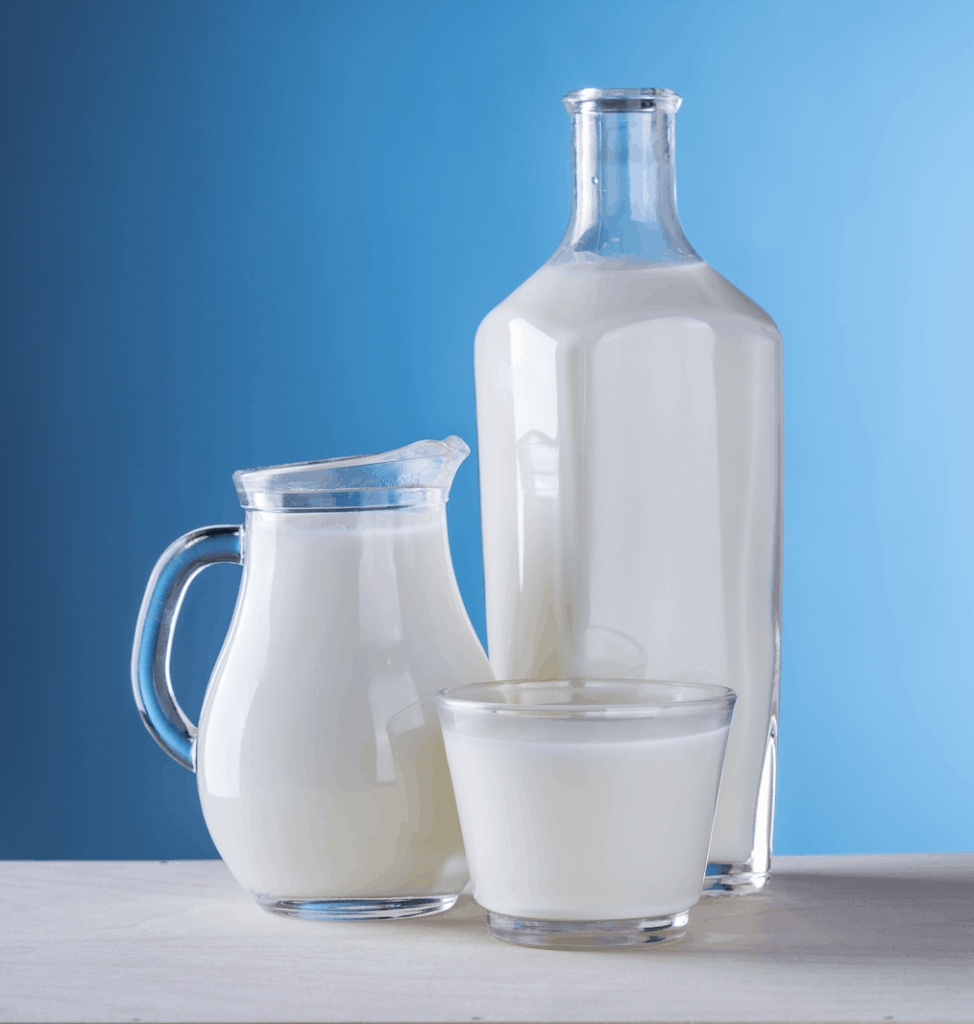 healthiest drinks for your child: milk  in a glass pitcher pictured against a blue background