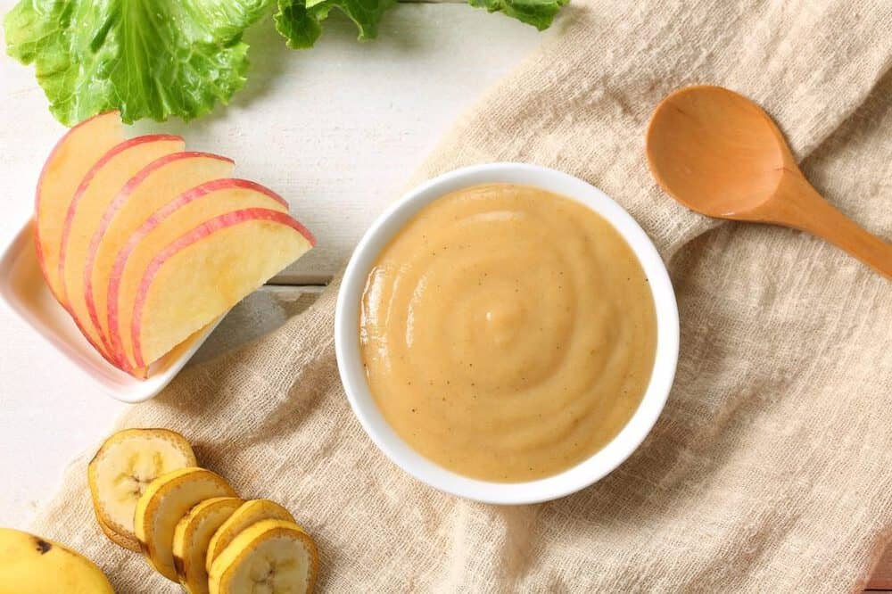 photo of apple and banana baby food puree, against a beige napkin. top view