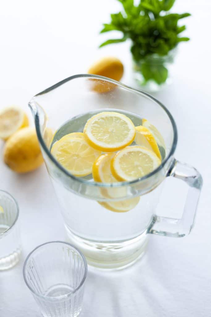 healthiest drinks for your child: water in a glass pitcher with cut lemon slices on top