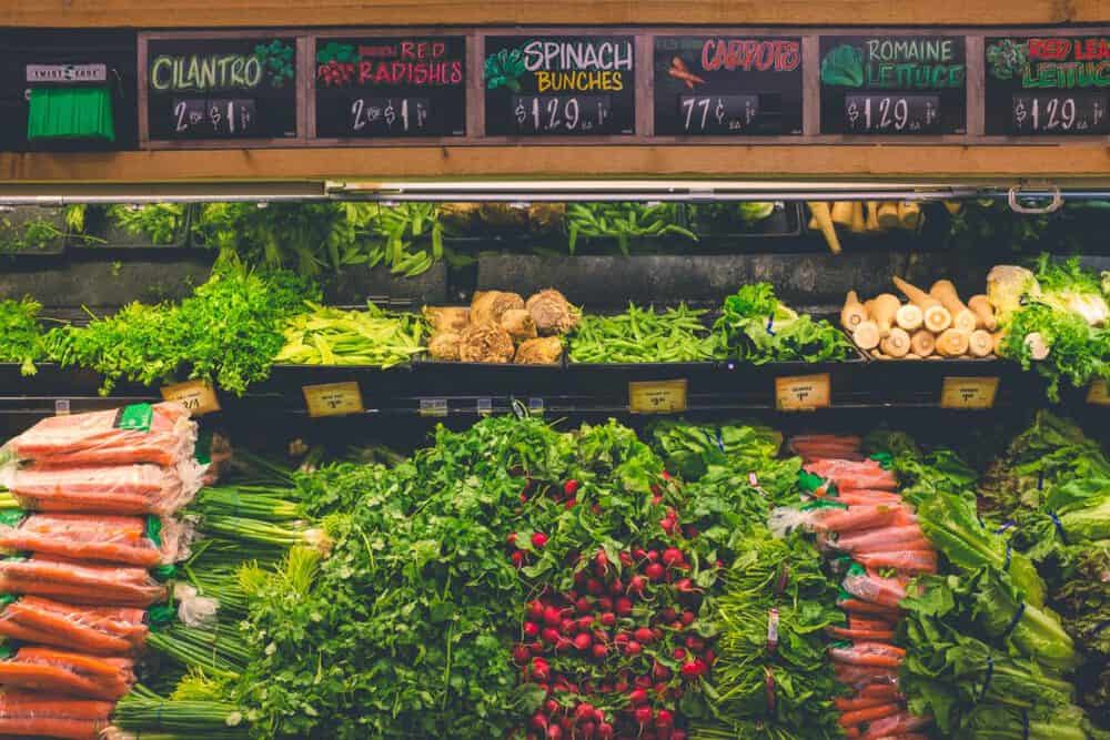 photo of produce at the grocery store: cilantro, radishes, spinach, carrots, romaine lettuce